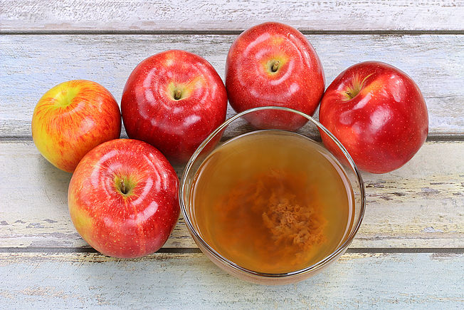 Fresh apples and a bowl of raw and unfiltered organic apple cide